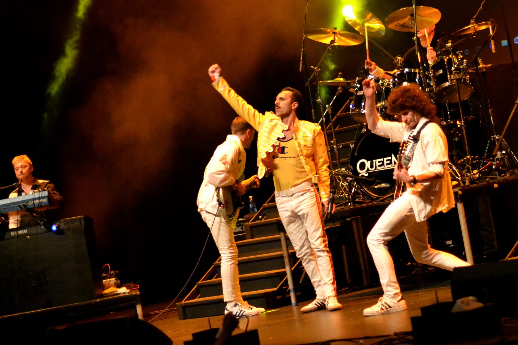 Flash Queen tribute band in iconic yellow jacket under dramatic stage lighting