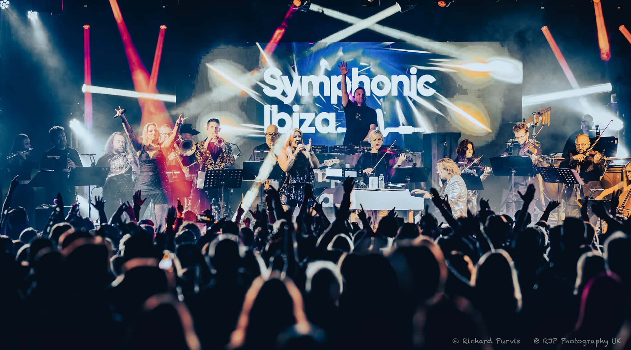 Symphonic Ibiza full ensemble performing with orchestra, vocalists and Symphonic Ibiza branding on stage