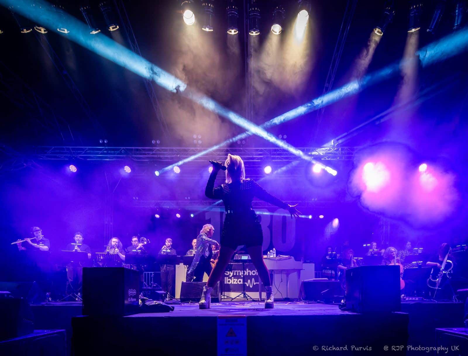 Symphonic Ibiza outdoor performance with full orchestra, DJ booth and purple stage lighting