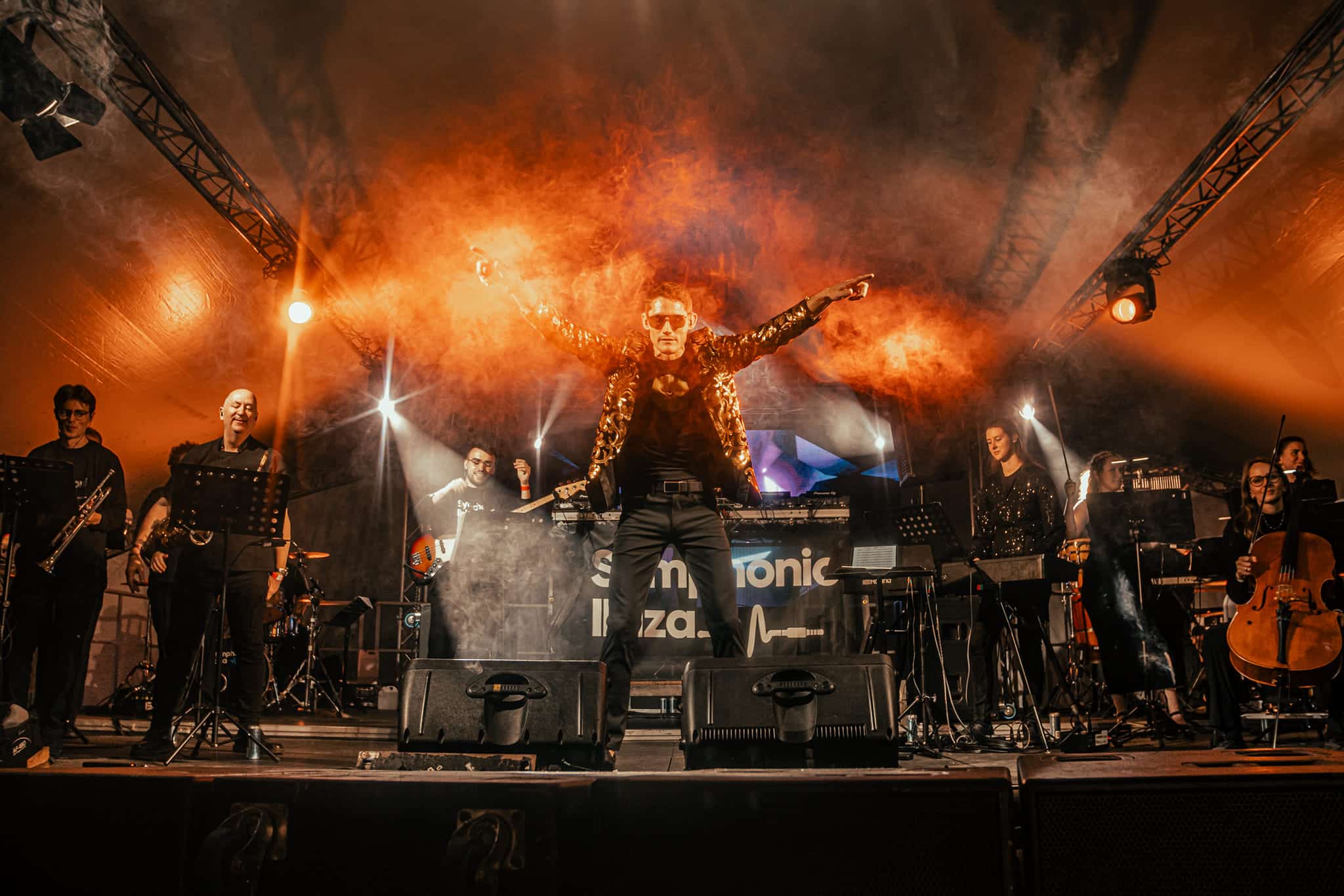 Symphonic Ibiza ensemble on stage with orange smoke and Symphonic Ibiza signage