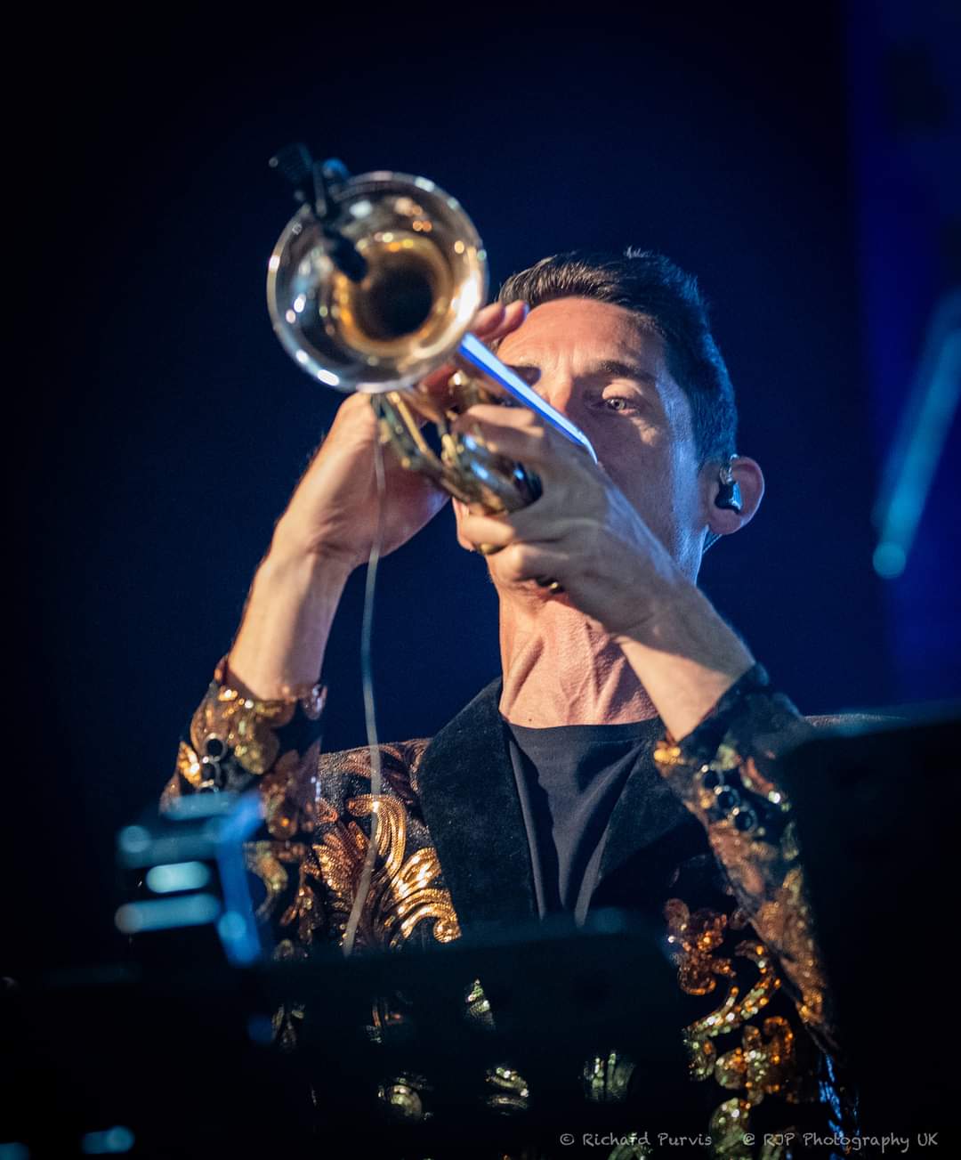 Symphonic Ibiza trumpet player in embroidered velvet jacket during live performance